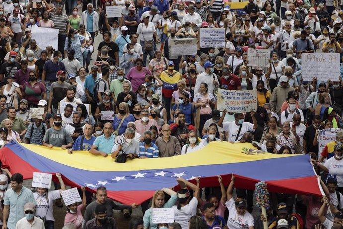 Archivo - 11 August 2022, Venezuela, Caracas: Demonstrators wave a large Venezuelan flag during a protest by public sector workers demanding better wages. Photo: Jesus Vargas/dpa