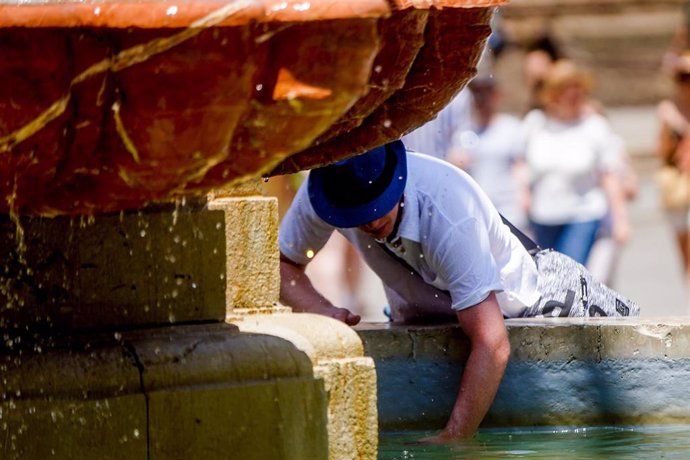 Archivo - Un turista se refresca en una fuente 