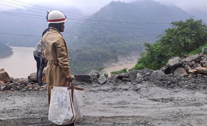 July 12, 2024, 21 Mile, West Bengal, INDIA: A worker uses an excavator to clear a landslide as local and other villagers as well as workers watches boulders fallen from hills at National Highway 10 (NH 10) which connects Siliguri to Sikkim state following