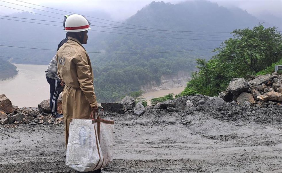 July 12, 2024, 21 Mile, West Bengal, INDIA: A worker uses an excavator to clear a landslide as local and other villagers as well as workers watches boulders fallen from hills at National Highway 10 (NH 10) which connects Siliguri to Sikkim state followi