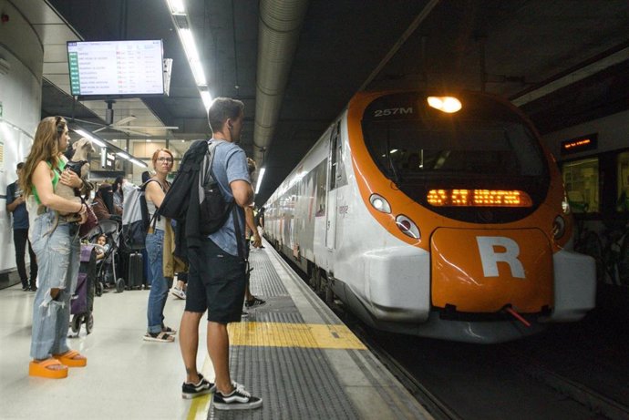 Archivo - Viajeros esperan en el andén de la estación barcelonesa de Sants a subir a un tren de Rodalies.