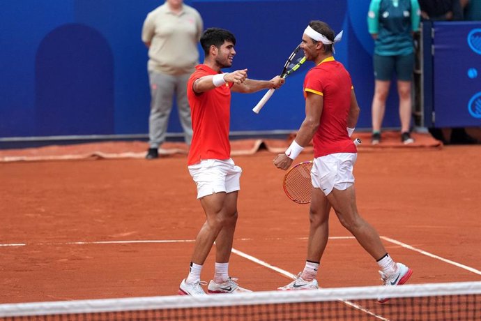 30 July 2024, France, Paris: Spainsh teannis players Carlos Alcaraz and Rafael Nadal (R) celebrate victory over Netherlands' Tallon Griekspoor and Wesley Koolhof (not pictured) during the men's doubles second-round match at Roland-Garros on the fourth day