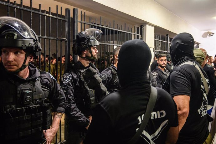 July 29, 2024, Kfar Yona, Israel: Armed and masked IDF reservists from the '100 force' stand in front of Israeli police officers blocking the Beit Lid base gate following its breach by right-wing activists. Israeli right-wing activists demonstrated with m