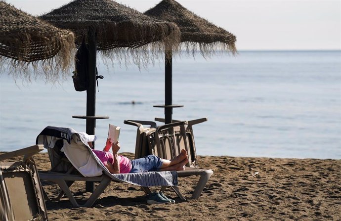 Archivo - Varias personas disfrutan tomando el sol en la playa de la Malagueta