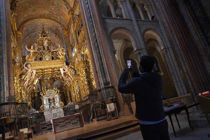 Archivo - Un turista saca una foto en el interior de la Catedral de Santiago.