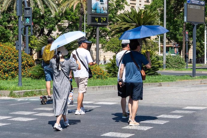 Varias personas al lado de un termómetro a 47 grados en Sevilla.