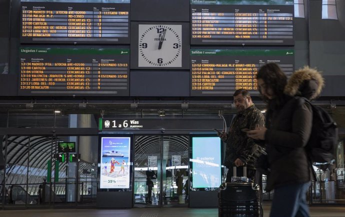 Archivo - Pasajeros en la estación ferroviaria de Santa Justa, con el panel de los horarios al fondo, en una imagen de archivo