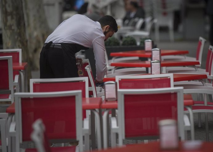 Archivo - Un camarero limpia las mesas de un bar en Sevilla. Imagen de archivo.