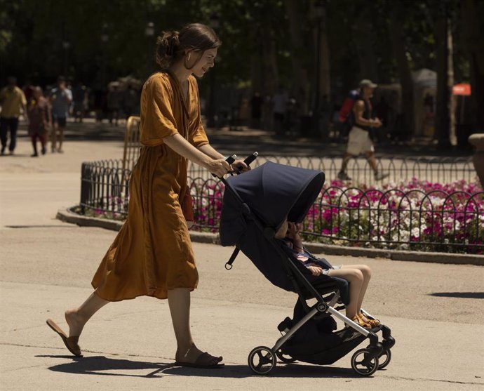 Archivo - Una mujer pasea a su hijo en el parque de El Retiro.