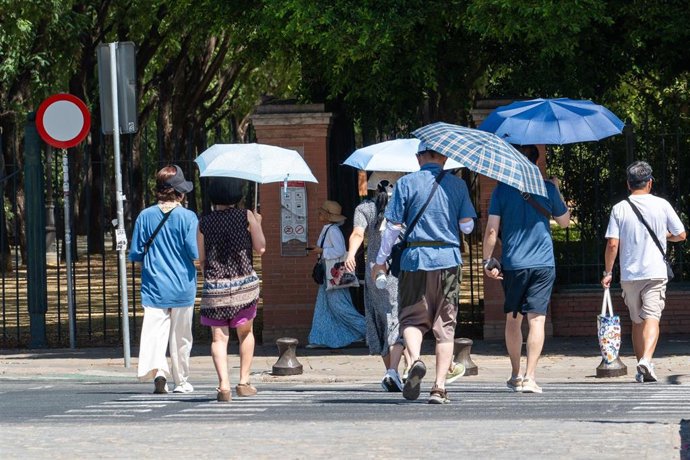 Imágenes de personas caminando con sombrillas por las calles de la capital hispalense (imagen de archivo). 