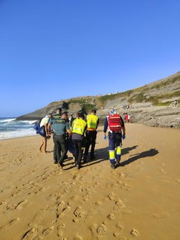 Bomberos del 112 portean a la mujer lesionada desde la playa de Antuerto a una zona accesible