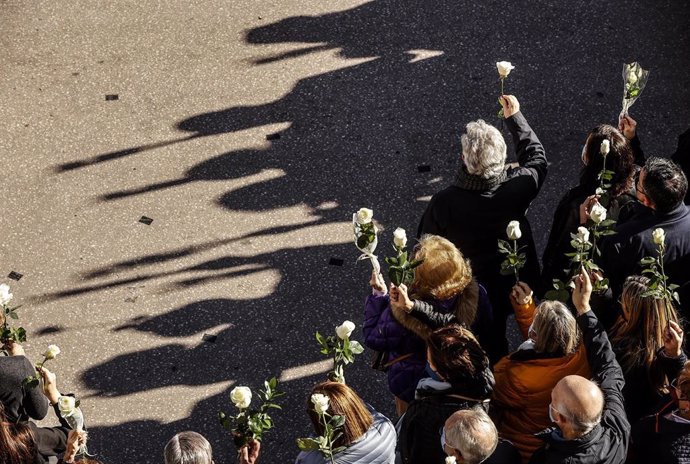 Archivo - Una multitud sostiene flores blancas en una concentración y minuto de silencio en memoria de una mujer víctima de violencia de género.