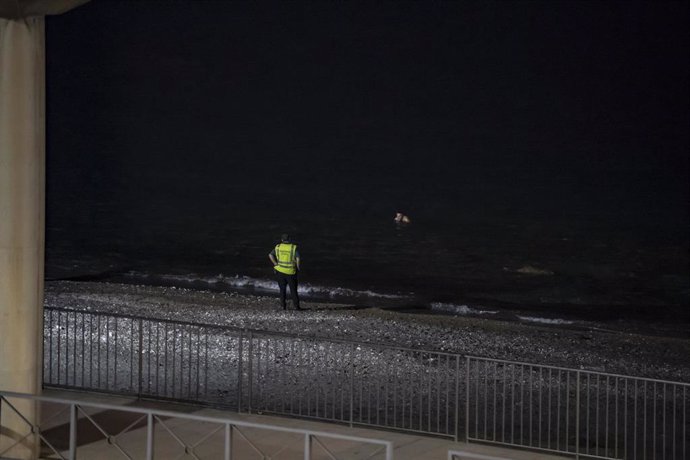 Un agente de la Guardia Civil espera la entrada a nado de un joven por la playa del Tarajal, a 5 de agosto de 2024, en Ceuta (España).