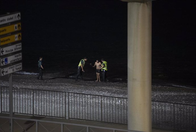 Un migrante detenido por dos agentes de la Guardia Civil tras entrar a nado por la playa del Tarajal en Ceuta, en una imagen de 5 de agosto.