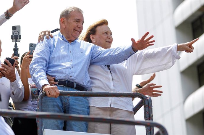 30 July 2024, Venezuela, Caracas: Edmundo Gonzalez Urrutia (L), opposition presidential candidate, and his wife Mercedes Lopez wave to supporters as they take part in a demonstration against the official results of the presidential election that declared 