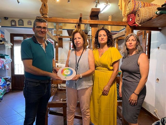 El delegado territorial de Empleo, Empresa y Trabajo Autónomo de la Junta en Granada, José Javier Martín, entrega el distintivo 'Andalucía, calidad artesanal' a la tejedora de la Alpujarra Ana Martínez