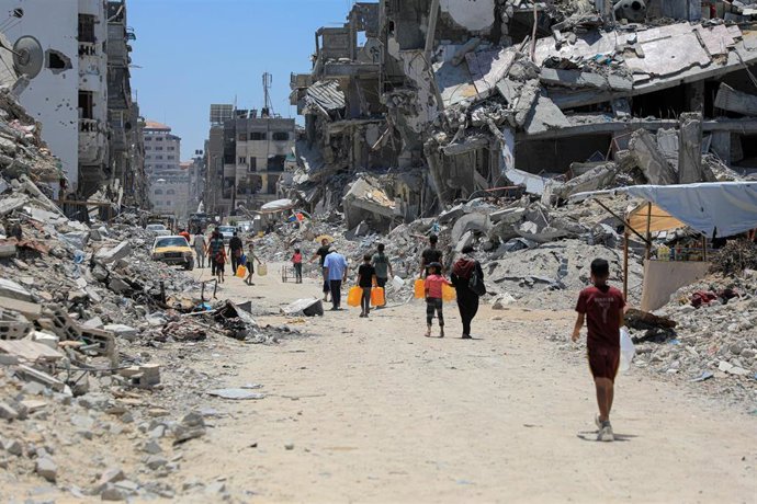 Archivo - GAZA, June 12, 2024  -- People are seen on a street with buildings destroyed in Israeli strikes in the southern Gaza Strip city of Khan Younis, on June 12, 2024. In Gaza, half of the population, or more than 1 million people, is expected to face