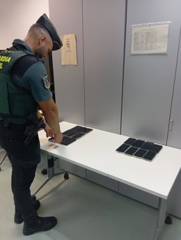 Un agente del Destacamento fiscal y de Fronteras de la Guardia Civil de Ibiza con los terminales móviles incautados