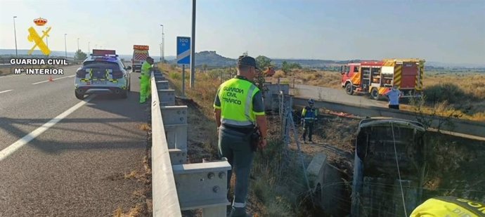 Agentes de la Guardia Civil y Bomberos junto al vehículo accidentado este domingo en Castejón del Puente (Huesca).