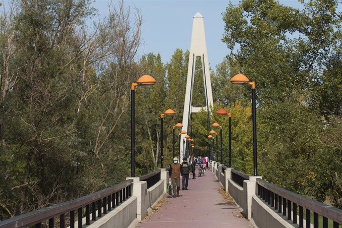 Archivo - Transeúntes caminan por la Pasarela del Ebro 