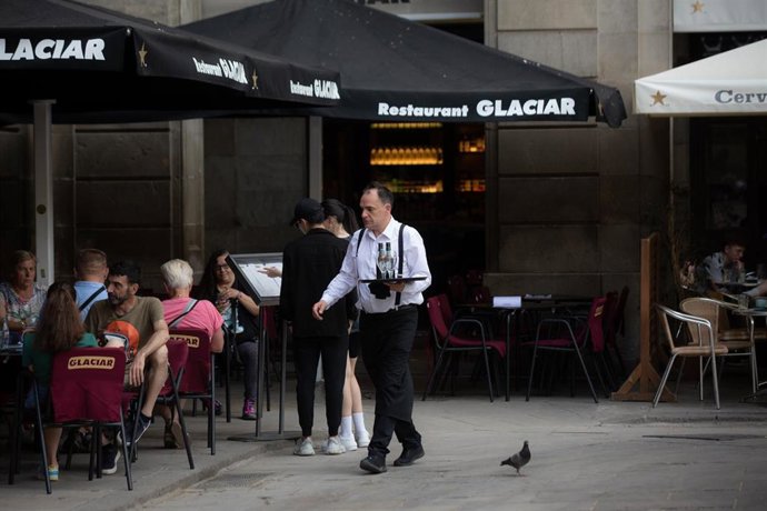 Archivo - Un camarero sostiene una bandeja en la plaza Real de Barcelona
