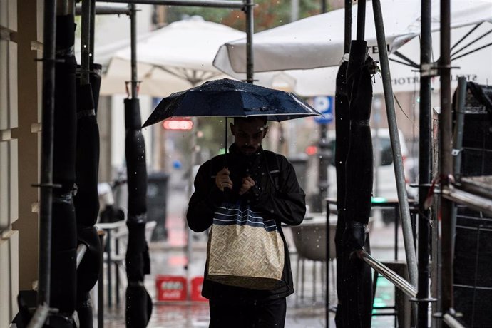 Archivo - Varias personas se resguardan de la lluvia con paraguas, a 3 de septiembre de 2023, en Madrid (España).