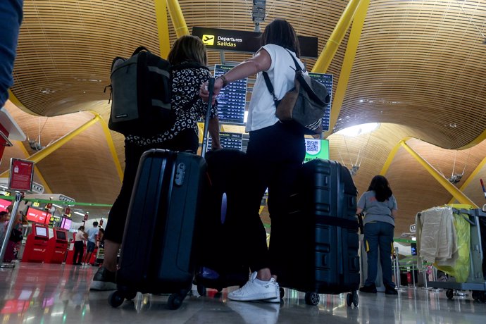 Varias personas observan el panel de salidas, con motivo de la operación salida del puente de agosto, en la T4, en el aeropuerto Adolfo Suárez Madrid-Barajas, a 14 de agosto de 2024, en Madrid (España).