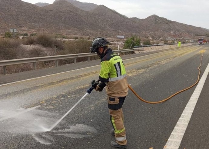 Un bombero limpiando el asfalta de pulpa de naranja