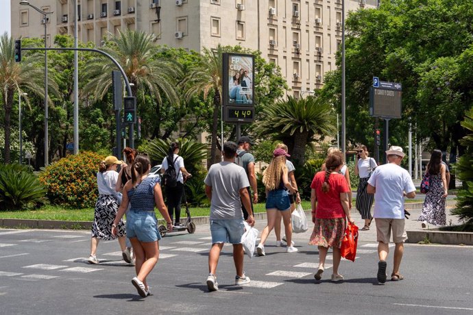 Un termómetro marca 45 grados a las 14.00 de la tarde junto a unos turistas paseando en Sevilla, Andalucía (España).