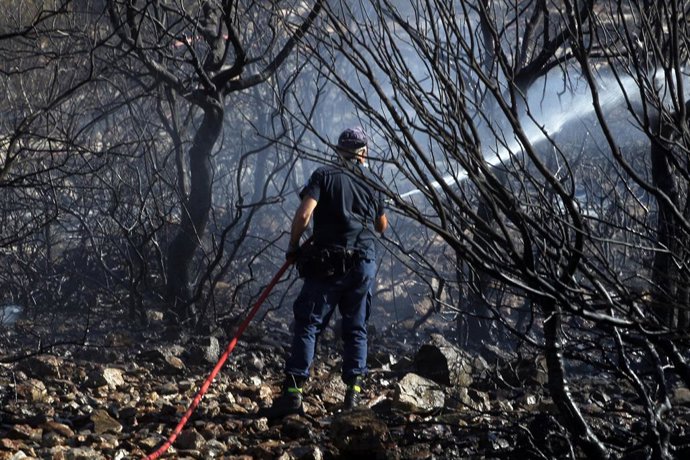 August 13, 2024, Kalivia, Attica, Greece: Firefighters extinguish a wildfire in Kalivia in East Attica region. Another fire broke out on Tuesday morning in low vegetation. At one point there were fears of a line of fires stretching for kilometres heading 