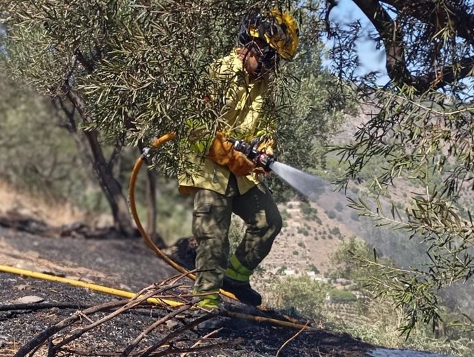 Un efectivo del Plan Infoca trabaja sobre el terreno para sofocar el incendio en la zona de la Peña Escrita, en Almuñécar (Granada)