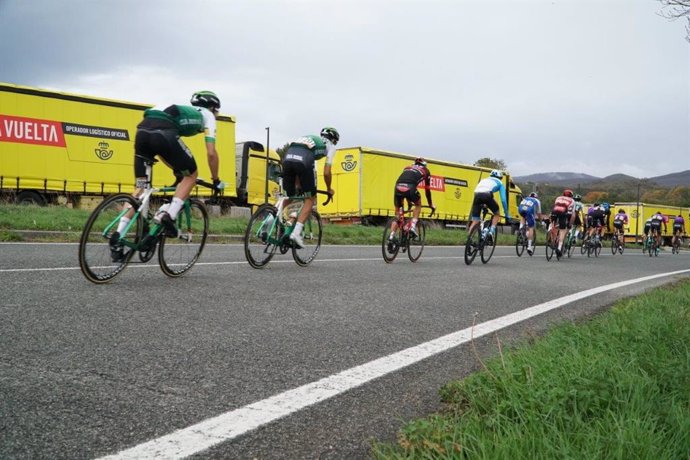 Archivo - Ciclistas de La Vuelta participando en la carrera camiones de Correos al fondo.