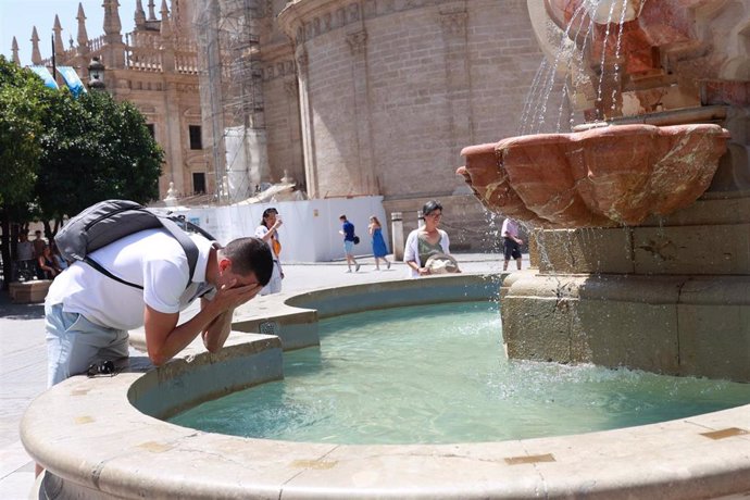 Un joven se refresca en una fuente para soportar las altas temperaturas. En Sevilla (Andalucía, España)