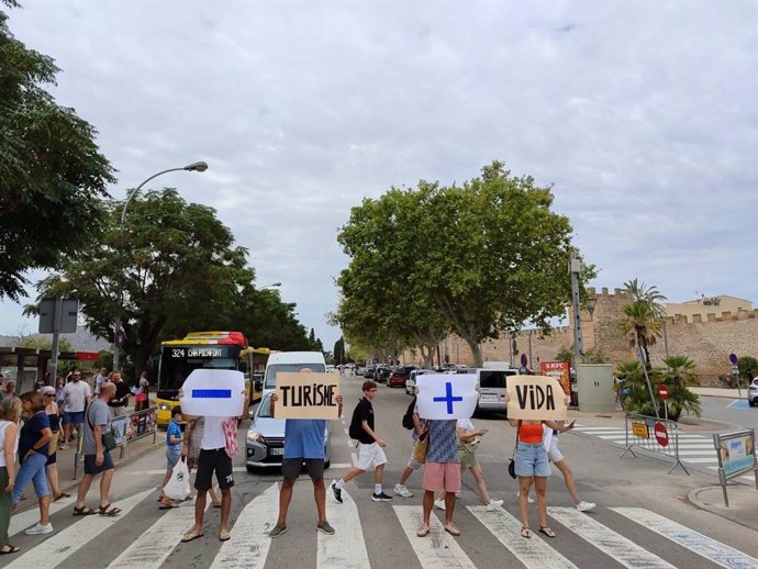 Miembros de Menys Turisme, Més Vida cortan el tráfico en Alcúdia para denunciar la saturación turística.