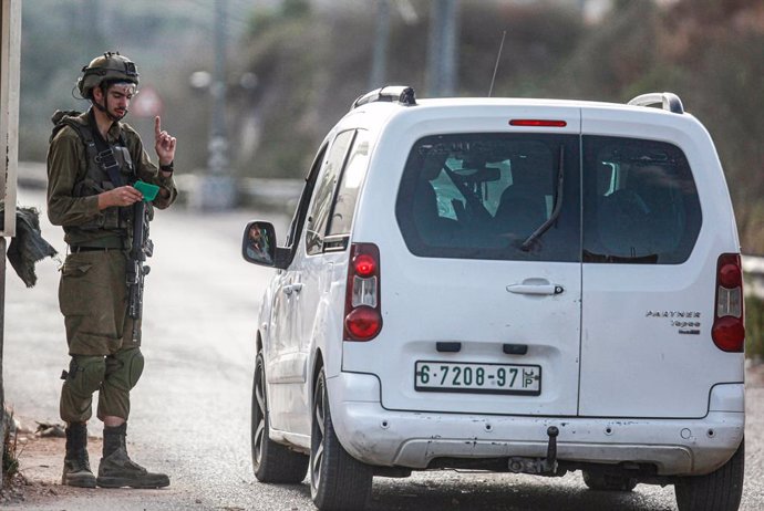 Archivo - July 6, 2023, Nablus, West Bank, Palestine: An Israeli soldier checks the phones of Palestinians who pass through an Israeli military point, near the site of the shooting of an Israeli soldier at the gate of the Jewish settlement of Kedumim in t