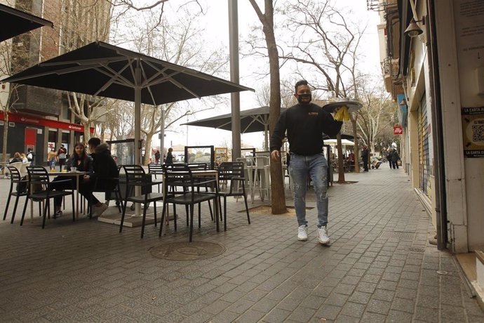 Archivo - Un camarero atiende a varios clientes en la terraza de un bar en Palma.