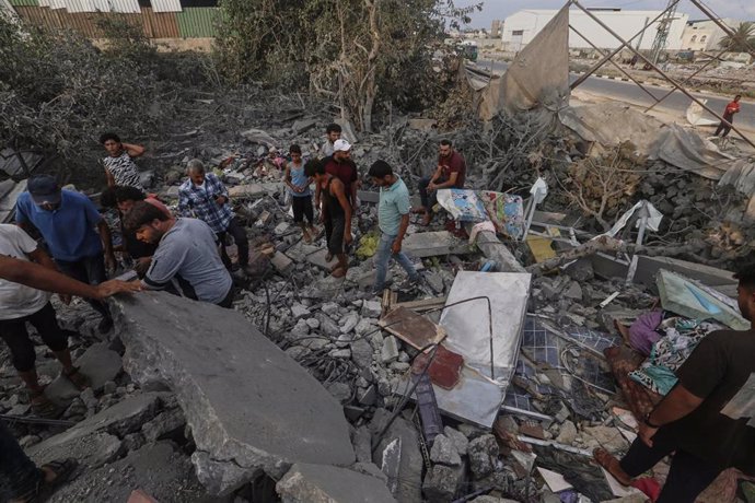 Un grupo de palestinos inspecciona los escombros de un edificio destruido en la Franja de Gaza