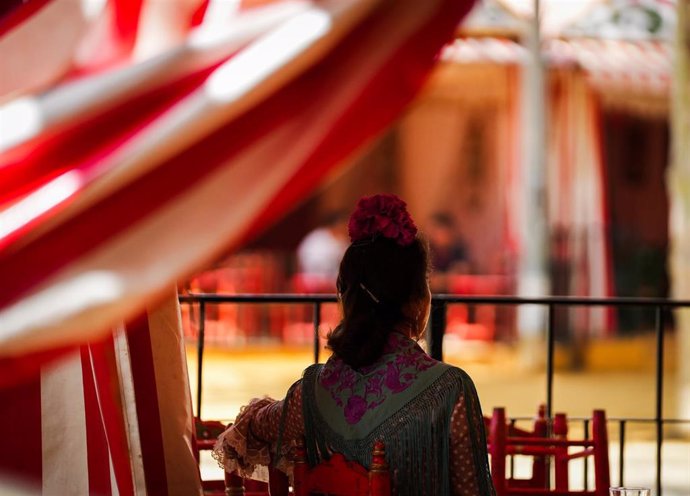 Archivo - Una mujer vestida de flamenca en una caseta de la feria