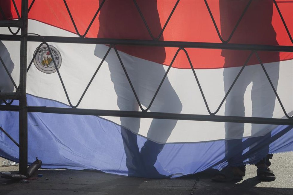 Archivo - May 11, 2023, Asuncion, Paraguay: People stand behind a banner depicting Paraguayan national flag as they gather during a demonstration against the alleged electoral fraud in the recent general elections held on April 30, in the vicinity of th