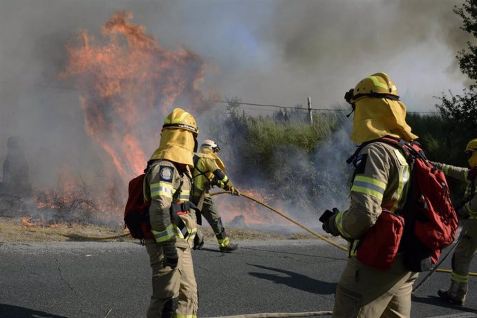 Varios bomberos tratan de apagar el fuego durante el incendio forestal en la parroquia de Oseira en San Cristovo de Cea, Ourense