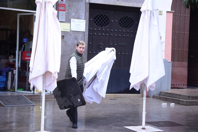 Archivo - Un camarero con una sombrilla en una terraza de Sevilla