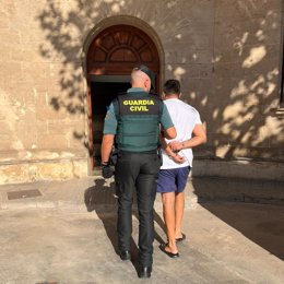 Un agente de la Guardia Civil acompaña a uno de los detenidos en Llucmajor.