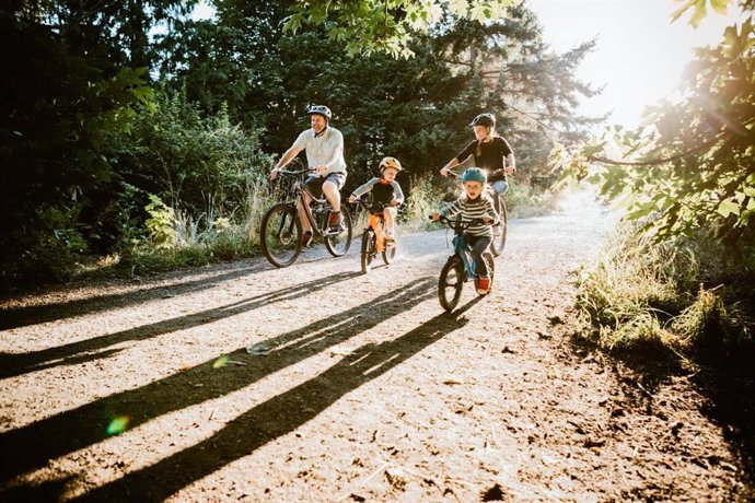 Archivo - Familia montando el bicicleta por el campo