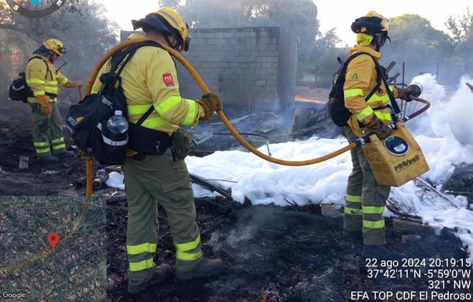 Bomberos del Plan Infoca apagan las llamas en el interior de una parcela de la urbanización La Mina, en Castilblanco de los Arroyos (Sevilla).