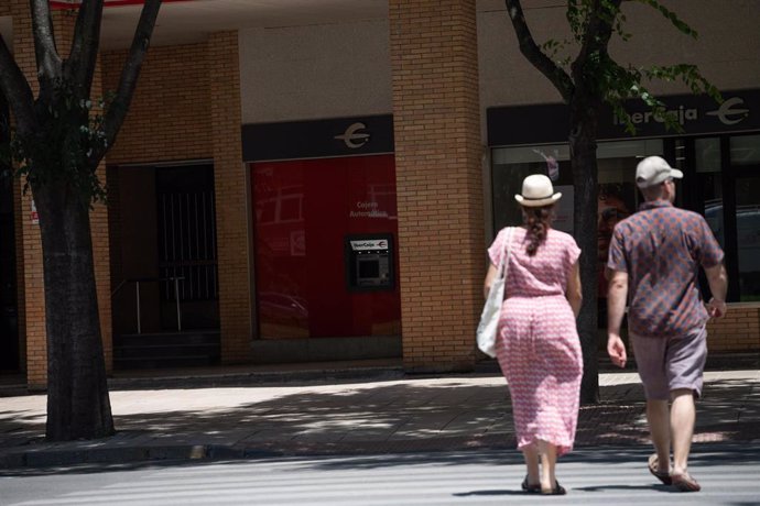 Archivo - Oos personas caminan por la calle en un día soleado.