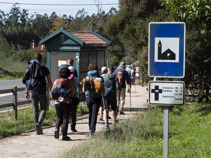 Archivo - Un grupo de peregrinos pasa frente a un cartel que indica el horario de misas mientras realizan el Camino de Santiago, en Santiago de Compostela, a 9 de octubre de 2021, en Santiago de Compostela, A Coruña, Galicia (España). 