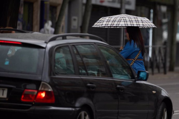 Archivo - Una mujer se protege de la lluvia con un paraguas