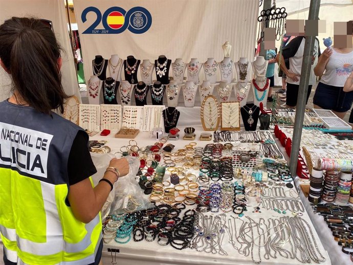 Una agente de la Policía Nacional inspecciona mercancía falsificada en un mercadillo del sur de Tenerife