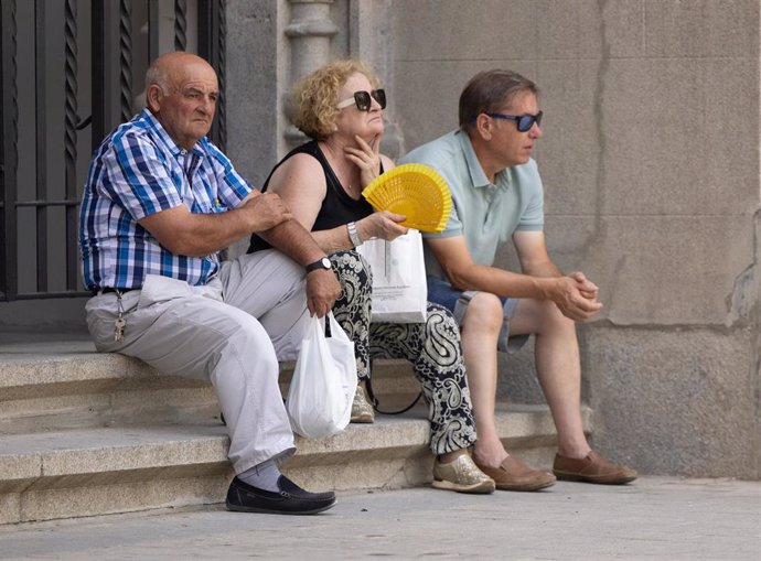 Varias personas se sientan en la sombra en Madrid (España).