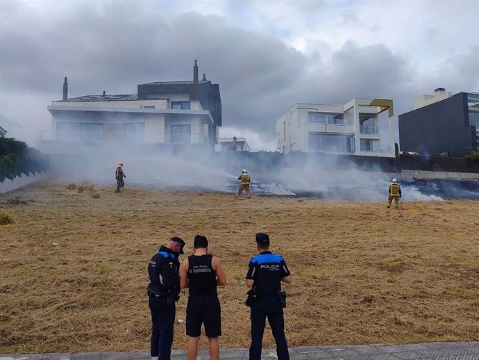 Bomberos y policía durante las labores de extinción del incendio en una parcela de Montecerrao, Oviedo